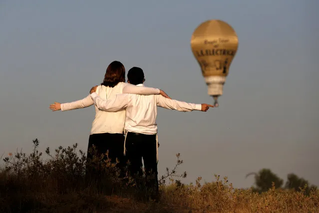 An Ultra-Orthodox Jewish couple stand together as hot air balloons fly overhead during a two-day international hot air balloon festival in Eshkol Park near the southern city of Netivot, Israel July 22, 2016. (Photo by Amir Cohen/Reuters)