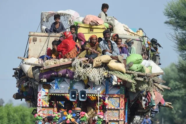 Displaced people sit on a tractor with their belongings as they make their way to reach safer place camp after fleeing from their flood hit homes following heavy monsoon rains in Shikarpur of Sindh province on August 30, 2022. Aid efforts ramped up across flooded Pakistan on August 30 to help tens of millions of people affected by relentless monsoon rains that have submerged a third of the country and claimed more than 1,100 lives. (Photo by Asif Hassan/AFP Photo)