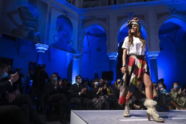 A model takes to the catwalk inside the 19th century building City Hall in Sarajevo, Bosnia, Thursday, December 16, 2021, during the presentation of a collection dubbed “No Nation Fashion”, a migrant-made fashion brand project. At the fashion show migrant models came out on the catwalks in designs meant to symbolize various stages of their journeys – the “nomadic” road away from home and the transit to new lives in new countries while the panel in the background read “We are strong”, and “We smile”. (Photo by AP Photo/Stringer)