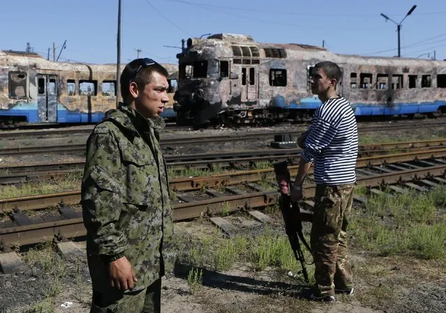 Pro-Russian separatists stand in front of destroyed trains at a railway station in the eastern Ukrainian town of Ilovaysk August 31, 2014. Russian President Vladimir Putin called on Sunday for immediate talks on “statehood” for southern and eastern Ukraine, although his spokesman said this did not mean Moscow now endorsed rebel calls for independence for territory they have seized. (Photo by Maxim Shemetov/Reuters)