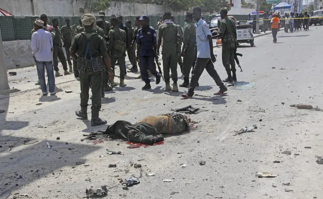 A body lies on the road as Somalis Security comb the area in a suicide car bomb attack outside The Criminal Investigation Department (CID) in Mogadishu, Somalia, Sunday, July 31, 2016. Two suicide bombers detonated an explosives-laden car outside the Criminal Investigation Department (CID) in Mogadishu, killing 9 people, including two bombers, and others were injured, a Somali police official said. (Photo by Farah Abdi Warsameh/AP Photo)