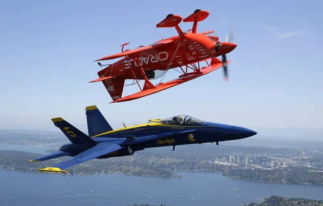 Aerobatic pilot Sean D. Tucker, top, flies inverted in his Team Oracle Challenger III biplane while in formation with U.S. Navy Lt. Ryan Chamberlain, the lead solo pilot for the Blue Angels, in a Boeing F/A-18 Hornet, near Seattle, Thursday, August 4, 2016. Tucker, the Blue Angels, and other aerobatic acts are in town to preform in the annual Seafair Air Show, which will take place Aug. 5-7 over Lake Washington in Seattle. (Photo by Ted S. Warren/AP Photo)