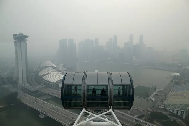 Tourists sit in a capsule on the Singapore flyer observatory wheel overlooking the skyline of the central business shrouded by haze in Singapore September 10, 2015. (Photo by Edgar Su/Reuters)