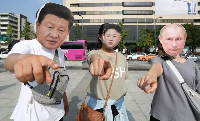 South Korean protesters wearing masks of Chinese President Xi Jinping (L), North Korean leader Kim Jong-Un (C) and Russian President Vladimir Putin (R) perform during a rally against the government's defense policy near the US Embassy in Seoul, South Korea, 12 August 2016. South Korea's government announced its the decision on 13 July, to allow the US to deploy the THAAD system in Seongju-gun to counter North Korea's missile threats. (Photo by Kim Chul-Soo/EPA)