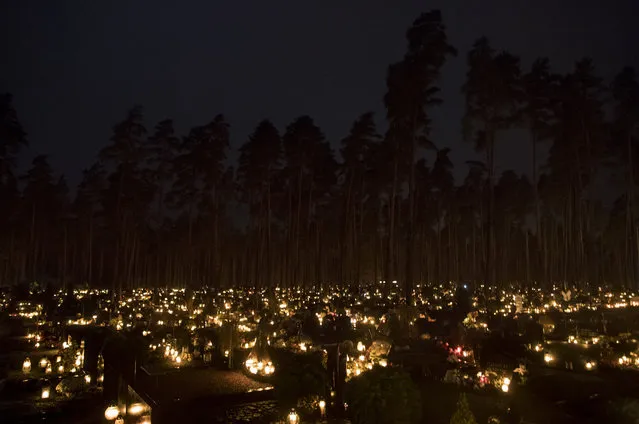 Candles are lit during All Saints Day at the cemetery in Vilnius in Vilnius, Lithuania, Wednesday, November 1, 2017. Candles illuminated tombstones in graveyards across Europe as people communed with the souls of the dead on Wednesday, observing one of the most sacred days in the Catholic calendar. (Photo by Mindaugas Kulbis/AP Photo)