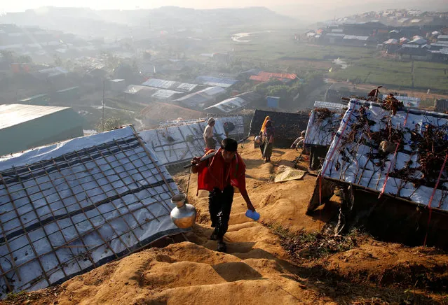 A Rohingya refugee walks uphill carrying a vessel filled with water at Palongkhali refugee camp, near Cox's Bazar, Bangladesh on November 7, 2017. (Photo by Navesh Chitrakar/Reuters)