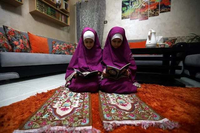Children of the Jordanian Imam Ahmad al Harasis read holy Koran at their home prior to Taraweeh prayer during the holy fasting month of Ramadan as prayers by worshippers in the holy places are suspended in Amman, Jordan on May 11, 2020. (Photo by Muhammad Hamed/Reuters)