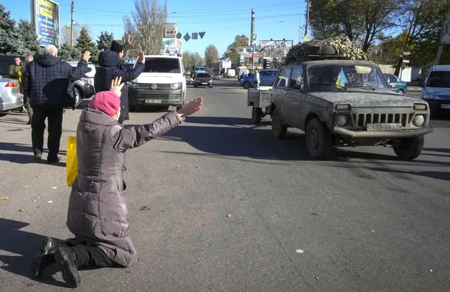 A woman kneels on the ground in front of passing Ukrainian Army car in Kherson, Ukraine, Tuesday, November 15, 2022. (Photo by Efrem Lukatsky/AP Photo)