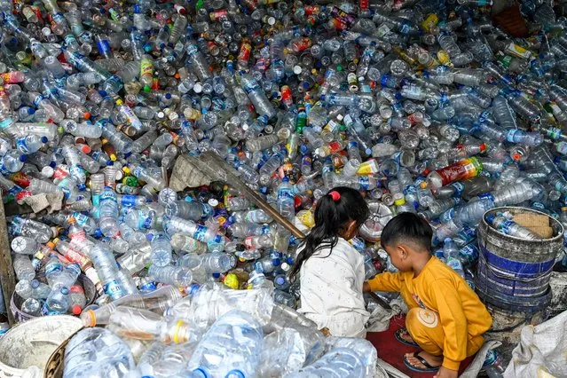Children play with plastic bottles at a waste collection site in Banda Aceh on October 28, 2022. (Photo by Chaideer Mahyuddin/AFP Photo)