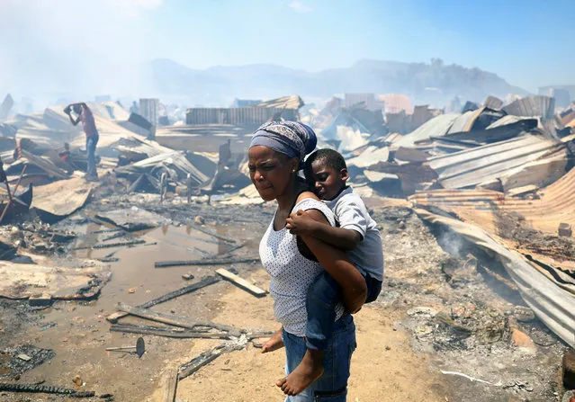 A woman and a child look at the destruction as a blaze destroyed many shacks in Masiphumelele township in Cape Town, South Africa on November 21, 2022. (Photo by Esa Alexander/Reuters)