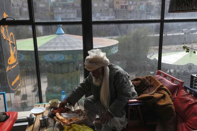 A Taliban member eats food in a restaurant in an amusement park in Kabul, Afghanistan on November 9, 2022. (Photo by Ali Khara/Reuters)