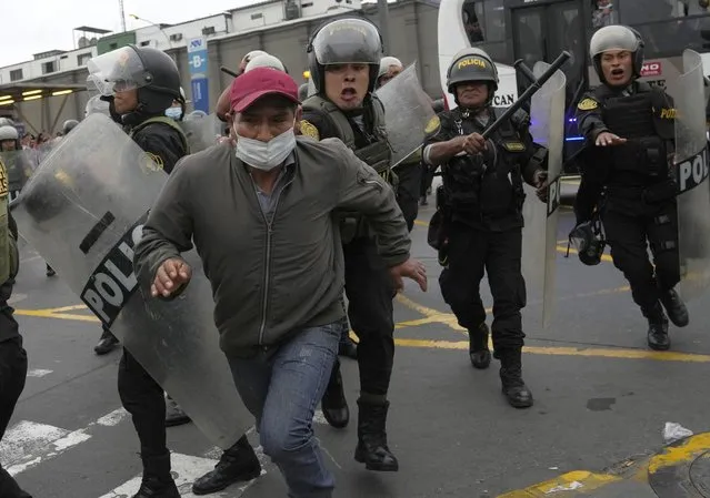 A riot police grabs hold of a supporter of former President Pedro Castillo outside the police station where Castillo arrived earlier, and where supporters had gathered and confronted riot police surrounding the station, in Lima, Peru, Wednesday, December 7, 2022. Peru's Congress removed Castillo from office Wednesday, voting to replace him with the vice president, shortly after Castillo decreed the dissolution of the legislature ahead of a scheduled vote to oust him. (Photo by Martin Mejia/AP Photo)