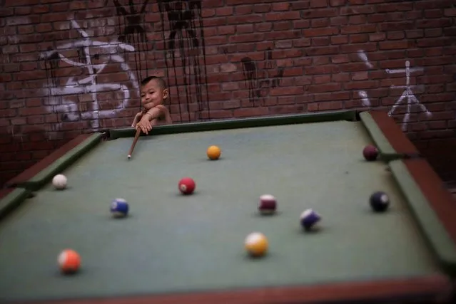 A young Chinese boy plays snooker with another boy, unseen, in a Hutong, or a traditional alleyway of Beijing, China, Tuesday, July 13, 2010. (Photo by Muhammed Muheisen/AP Photo)