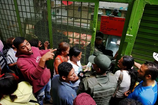 Venezuelan soldiers control the crowd as people queue trying to buy basic food during a special inspection to a municipal market in Caracas, Venezuela July 15, 2016. (Photo by Carlos Garcia Rawlins/Reuters)