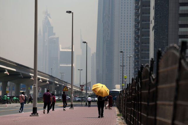 People cover up to protect themselves on a hot dusty day. Business Bay, Dubai on May 21, 2025. (Photo by Chris Whiteoak/The National)