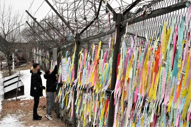 A woman hangs a ribbon wishing for the reunification of the two Koreas on a fence as she visit the Imjingak Pavilion, near the border with the North, to celebrate the Lunar New Year in Paju, South Korea, Sunday, January 22, 2023. (Photo by Ahn Young-joon/AP Photo)