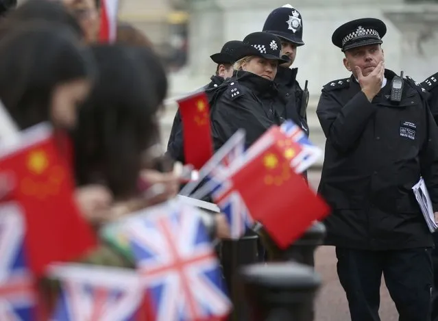 Police officers stand on duty near supporters of China's President Xi Jinping as they wait on the Mall for him to pass during his ceremonial welcome, in London, Britain, October 20, 2015. (Photo by Neil Hall/Reuters)