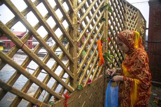 A Nepalese woman offers prayers in front of the closed gate of Pashupatinath temple during the holy month of Shrawan in Kathmandu, Nepal, Monday, July 20, 2020. Autumn is the festival season in predominantly Hindu Nepal, where religion, celebrations and rituals are big parts of lives, but people this year will have to scale down their rituals within their homes. Nepalese authorities imposed a strict coronavirus lockdown in March that was eased in July. But the ban of outdoor festivals and religious gatherings continues and temples remain locked. (Photo by Niranjan Shrestha/AP Photo)