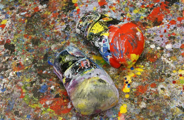 In this photo taken on Tuesday, September 6, 2016 the gloves used by Omar Hassan to paint canvas lie on the ground in Milan, Italy. When he creates art work, Omar Hassan doesn’t get out paint brushes. He gets out his boxing gloves. Hassan, a 29-year-old artist and boxer, has combined his two passions, with the goal to bring the disciplines closer. Hassan, born in Milan to an Italian mother and Egyptian father, creates the works by dipping his glove in paint, and punching the canvas stretched over cardboard to keep it from breaking. He calls the series “Breaking Through Milano” His paintings sell from 8,000 to 40,000 euros, which he calls “a great satisfaction, but not the goal”. (Photo by Antonio Calanni/AP Photo)