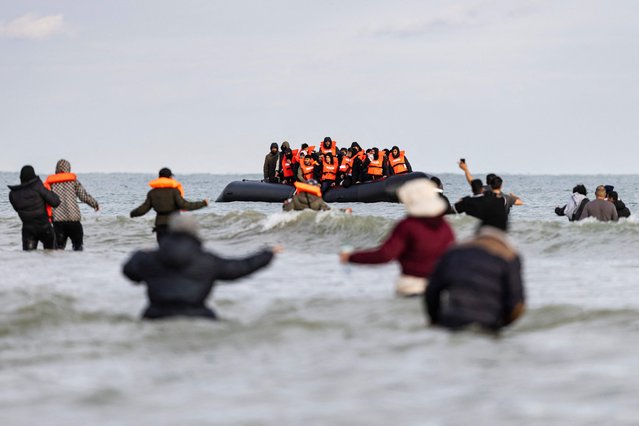 Migrants wave to a smuggler's boat in an attempt to cross the English Channel, on the beach of Gravelines, near Dunkirk, northern France on April 26, 2024. Five migrants, including a seven-year-old girl, died on April 23, 2024 trying to cross the Channel from France to Britain, local authorities said, just hours after Britain passed a controversial bill to deport asylum seekers to Rwanda. (Photo by Sameer Al-Doumy/AFP Photo)