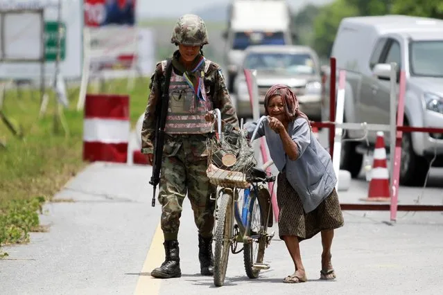 A woman pushes her bicycle through a checkpoint manned by Thai security forces in the troubled southern province of Yala March 27, 2013. The first round of formal peace talks between Thai government and the insurgent group Barisan Revolusi Nasional (BRN) will take place on March 28 and will be mediated by Malaysia. Although the first round is set for Thursday, there has been no halt in the fighting and people in the region see no early end to one of Southeast Asia's bloodiest conflicts. (Photo by Surapan Boonthanom/Reuters)