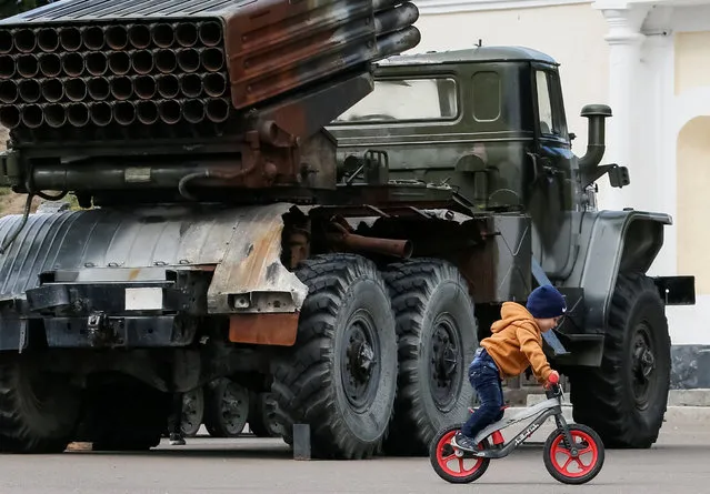 A boy rides a bicycle near a BM-21 Grad multiple rocket launcher system at an exhibition of military weapons and vehicles seized from pro-Russian separatists during fighting in eastern Ukraine, in central Kiev, Ukraine, September 21, 2016. (Photo by Gleb Garanich/Reuters)