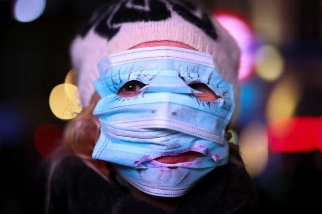 A woman uses protection masks to cover her face as protestors from the Million Mask March and anti lockdown protesters demonstrate, amid the coronavirus (COVID-19) outbreak in London, Britain on November 5, 2020. (Photo by Henry Nicholls/Reuters)