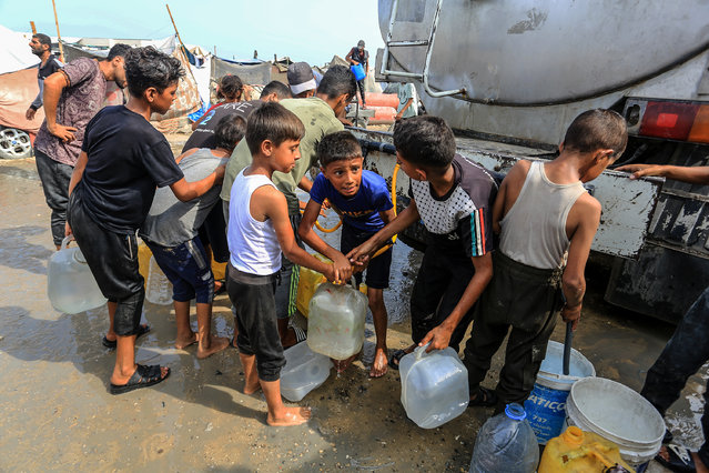 An aid truck distributes water to Palestinians in Khan Yunis, Gaza, where residents carry the supplies in plastic jerrycans amid a worsening water crisis, on August 13, 2025. Israeli attacks have severely damaged the city's infrastructure, leaving much of the population without access to clean drinking water due to destroyed wells and storage facilities. (Photo by Abed Rahim Khatib/Anadolu via Getty Images)