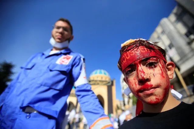 A medic stands near a Shi'ite Muslim boy with his face covered in blood after he was cut on the forehead with a razor during a religious procession to mark Ashura in Nabatiyeh town, southern Lebanon, October 12, 2016. (Photo by Ali Hashisho/Reuters)