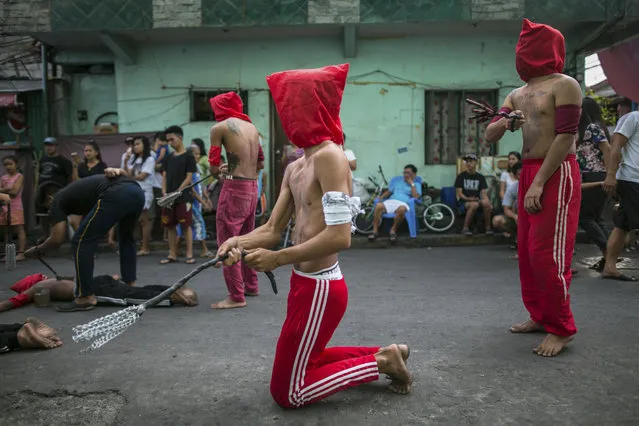 Male penitents in red hoods whip themselves on a street as residents watch from the sidelines in Mandaluyong City, Philippines, Thursday, March 29, 2018. Despite Catholic Church officials discouraging the tradition, hundreds of Filipinos still practice self-flagellation on Maundy Thursday as a way to atone for their sins and to commemorate the suffering of Jesus Christ. (Photo by Iya Forbes/AP Photo)