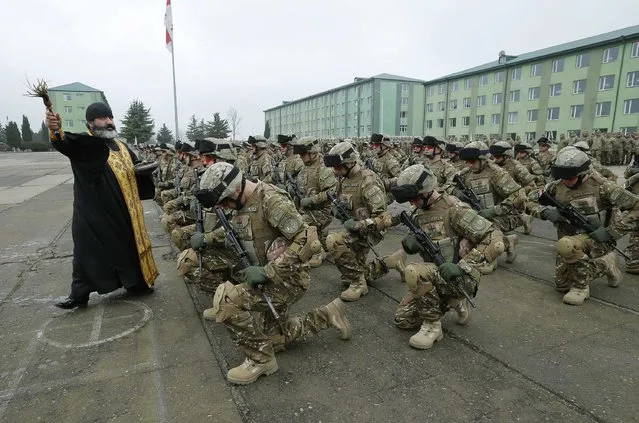 A priest blesses servicemen during a farewell ceremony at the Vaziani military base outside Tbilisi, December 16, 2014. According to Georgia's Defence Ministry, a joint company from the IV mechanized brigade of the Georgian Armed Forces is departing to Afghanistan to take over from another Georgian unit, as part of the International Security Assistance Force (ISAF), NATO military operation. (Photo by David Mdzinarishvili/Reuters)