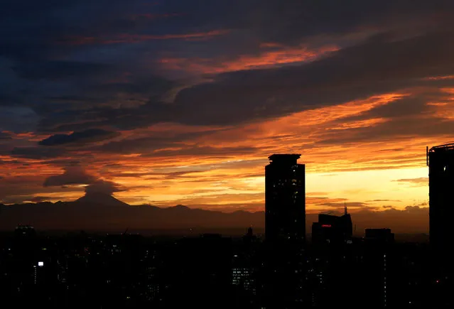 The silhouette of Japan's highest mountain Mount Fuji is seen beyond buildings in the dusk in Tokyo, Japan September 12, 2017. (Photo by Issei Kato/Reuters)