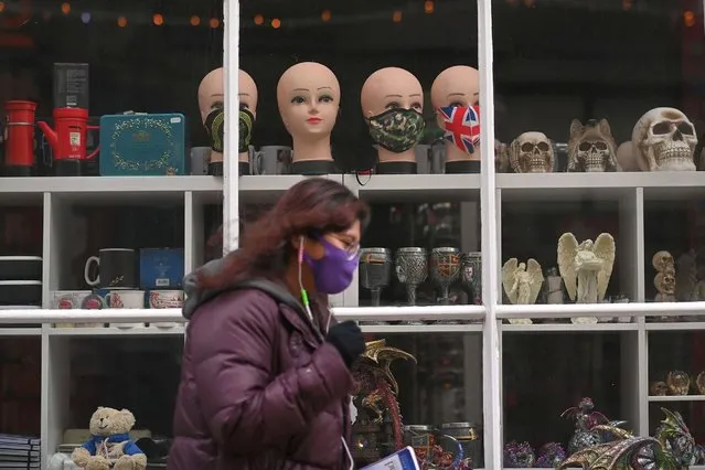 A woman wearing a mask because of the coronavirus pandemic walks past masks displayed on mannequins in the window of a closed shop in Canterbury, southern England on November 23, 2020. British Prime Minister Boris Johnson was to announce on Monday a major testing programme in areas with the highest coronavirus infection rates as the country re-enters a system of tiered restrictions. (Photo by Ben Stansall/AFP Photo)