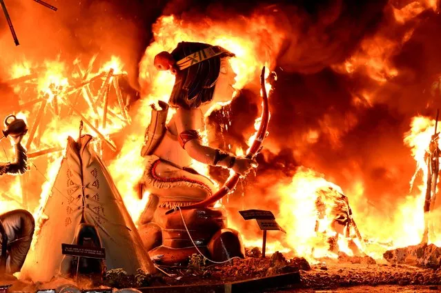 This photograph shows Ninots (cardboard figurines) in a “falla” (a huge ornate cardboard sculpture made to eventually be burnt) burning on the last night of the Fallas Festival in Valencia, on March 19, 2023. The fallas, gigantic cardboard structures that portray current events and celebrities in which individual figures, or “ninots” are placed, are burned in the streets of Valencia on March 19 as a tribute to San Jose (Saint Joseph), patron saint of the carpenters' guild. (Photo by Jose Jordan/AFP Photo)