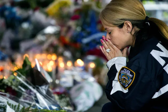New York Police Department Lt. Tanisha Gurley visits a makeshift memorial, Tuesday, December 23, 2014, near the site where NYPD officers Rafael Ramos and Wenjian Liu were murdered in the Brooklyn borough of New York. Police say Ismaaiyl Brinsley ambushed the two officers in their patrol car in broad daylight Saturday, fatally shooting them before killing himself inside a subway station. (Photo by Craig Ruttle/AP Photo)