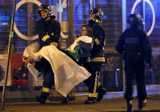 French fire brigade members aid an injured individual near the Bataclan concert hall following fatal shootings in Paris, France, November 13, 2015. (Photo by Christian Hartmann/Reuters)