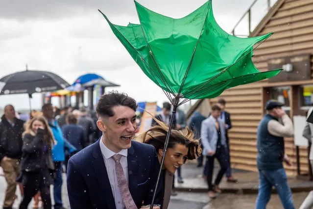 Racegoers shield themselves from the rain and wind at the Fairyhouse Easter Festival in Fairyhouse, Co. Meath, Ireland on April 10, 2023. (Photo by Morgan Treacy/Inpho)