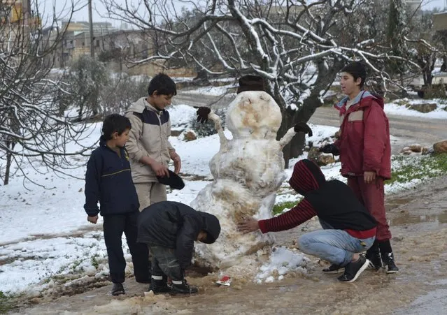 Boys build a snowman during a winter storm in Jabal al-Zawiya, in the southern countryside of Idlib January 7, 2015. A storm buffeted the Middle East with blizzards, rain and strong winds on Wednesday, keeping people at home across the region and raising concerns for Syrian refugees facing freezing temperatures in flimsy shelters. (Photo by Reuters/Stringer)
