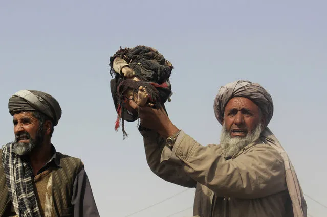 An Afghan man holds up the body of a child that was killed during clashes between Taliban and Afghan security forces in Kunduz province north of Kabul, Afghanistan, Thursday, November 3, 2016, Authorities say a joint raid by U.S. and Afghan forces targeting senior Taliban commanders killed two American service members and 26 civilians. Afghan officials said they were still investigating the attack and its civilian casualties, some of which may have been caused by the airstrikes. (Photo by Najim Rahim/AP Photo)