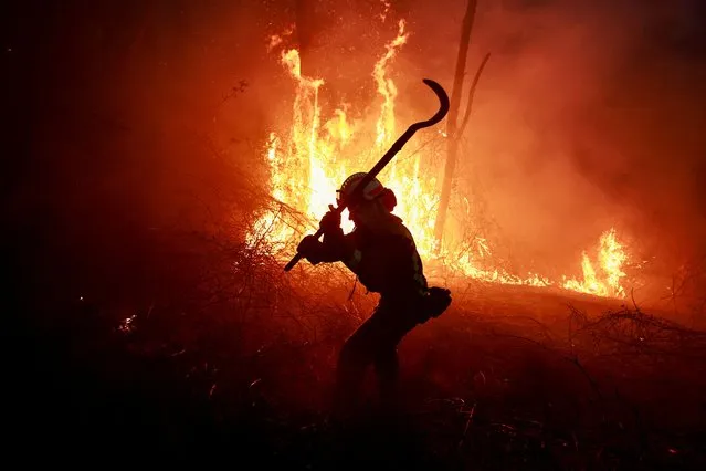 A Galician firefighter tackles flames in a forest during an outbreak of wildfires following a prolonged period of drought and unusually high temperatures, in Piedrafita, Asturias, Spain on March 31, 2023. (Photo by Vincent West/Reuters)