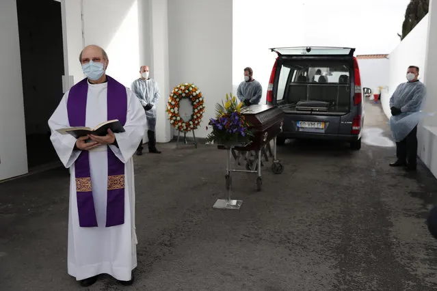 A priest says a few words during a brief ceremony outdoors before the cremation of a COVID-19 victim at a cemetery in Alcabideche, outside Lisbon, Wednesday, February 3, 2021. Portugal is facing a pandemic surge that has made it the world's worst-hit country by size of population. (Photo by Armando Franca/AP Photo)