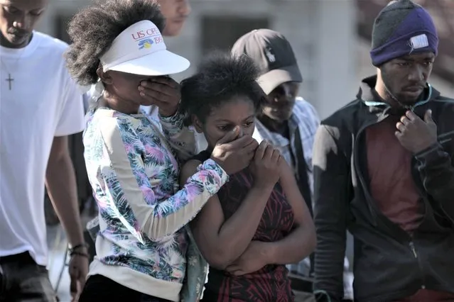 Bystanders look at the bodies of alleged gang members that were set on fire by a mob after they were stopped by police while traveling in a vehicle in the Canape Vert area of Port-au-Prince, Haiti, Monday, April 24, 2023. (Photo by Joseph Odelyn/AP Photo)