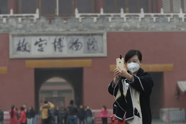 A woman takes a selfie with her mobile phone in front of an entrance to the Forbidden City amid heavy smog after the city issued its first ever "red alert" for air pollution, in central Beijing, China, December 8, 2015. (Photo by Reuters/China Daily)