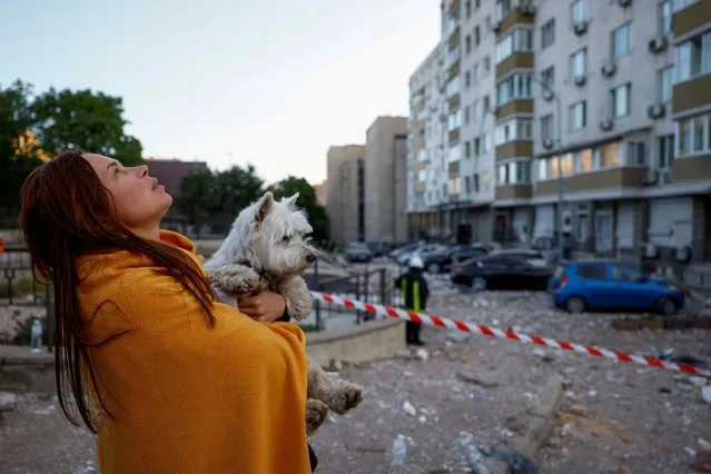 A woman with a dog looks at her apartment building heavily damaged during a massive Russian drone strike, amid Russia's attack on Ukraine, in Kyiv, Ukraine on May 30, 2023. (Photo by Valentyn Ogirenko/Reuters)