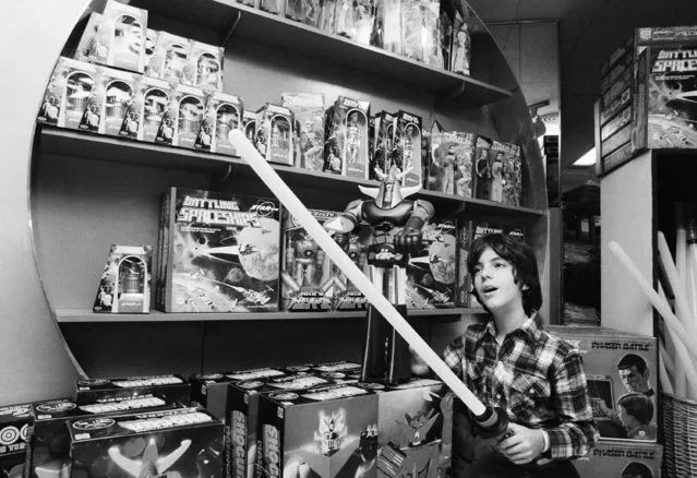 Haik Gazarian, 11, from Caracas, Venezuela, who now lives in New York, tries to cut a toy “Force Wand”,  an illuminated toy sword inspired by the film “Stars Wars”, during the visit to the toy department store, on Wednesday December 22, 1977. In the background are a number of other toys inspired by the current popularity of “Space Opera” type films. (Photo by Marty Lederhandler/AP Photo)