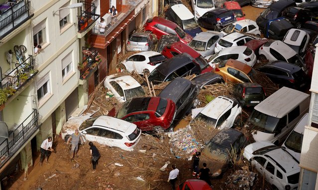 Residents look at cars piled up after being swept away by floods in Valencia, Spain, Wednesday, October 30, 2024. (Photo by Alberto Saiz/AP Photo)