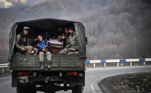 Armenian soldiers sit in the back of a truck as they drive along a road outside Kalbadjar on November 15, 2020. Azerbaijan said on November 15, 2020, it had agreed to extend a deadline for Armenia to withdraw from a disputed district as part of a peace accord that ended six weeks of fierce fighting over the Nagorno-Karabakh region. Armenia lost around 2300 dead during the military conflict over this breakaway region. (Photo by Alexander Nemenov/AFP Photo)