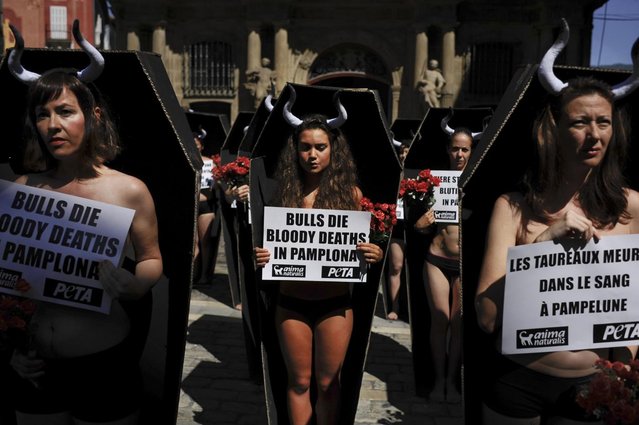 Anti-bullfighting demonstrators protest  against bulls runs, while standing in cardboard coffins and holding red flowers, on the Ayuntamiento Square in Pamplona northern Spain on Friday July 5, 2013. On July 6, the San Fermin festival will begin with the ''txupinazo'' , the opening ceremony with people participating in bull runs, music and dance, through the old street of the city. (AP Photo/Alvaro Barrientos)