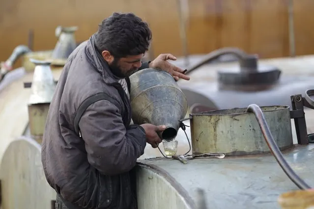 A worker inspects the final fuel product at a makeshift oil refinery site in Marchmarin town, southern countryside of Idlib, Syria December 16, 2015. (Photo by Khalil Ashawi/Reuters)