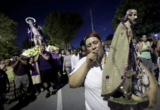 Josefina Sanjuan (C) smokes a cigar as she carries a statue of Saint Lazarus during a procession near “El Rincon de San Lazaro” church in Hialeah, Florida, USA, 17 December 2015. Saint Lazarus is one of the most popular Saints for Cubans, this worship emerged of the catholic and Yoruba religions and it is related to a poor leprous man, a friend of Jesus, revived in a biblical parable. (Photo by Cristobal Herrera/EPA)